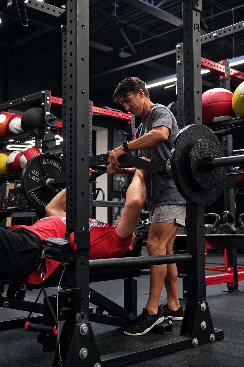 Christian Lauer coaching an Alpha Athletics member during a bench press